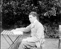 Purdy sitting at garden table with book Original caption: Purdy sitting at garden table with book